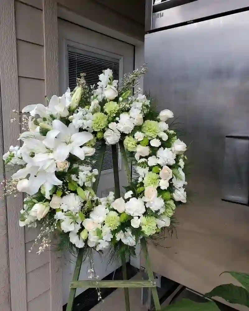 A white funeral tribute wreath by BloomHaus